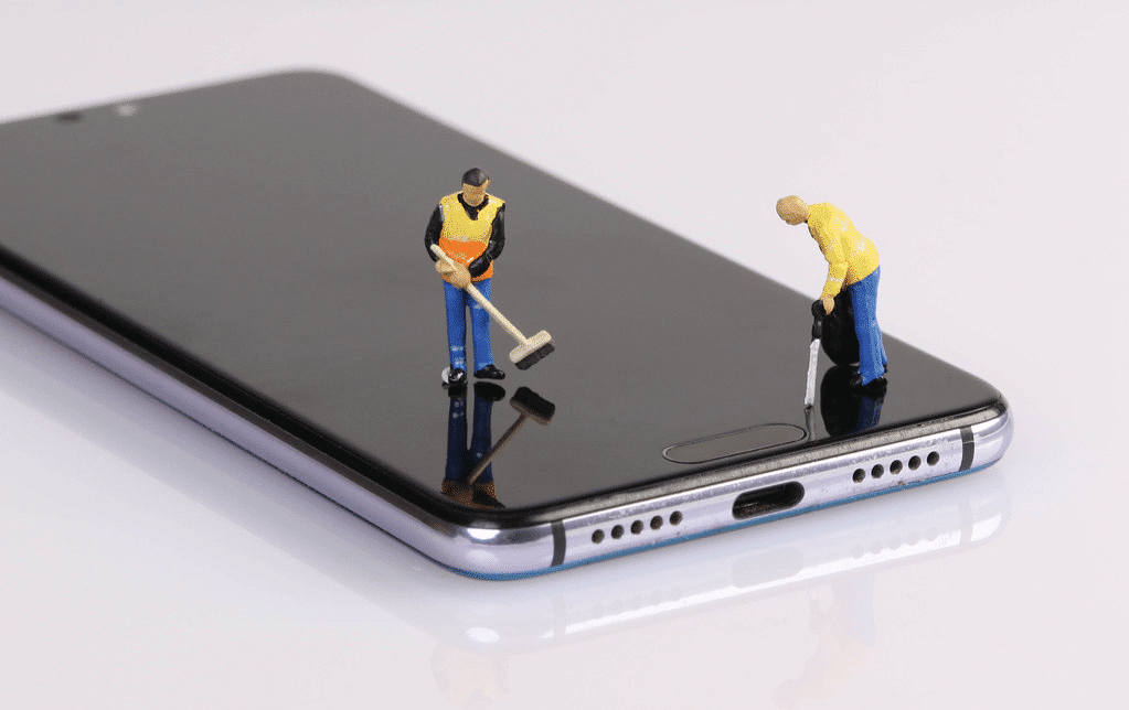 Two small figures of workers with brooms and leaf blowers posed to be 